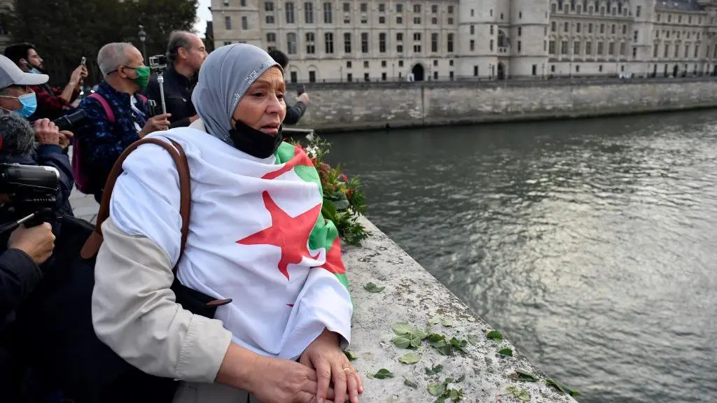 سيدة تقف أمام نهر السين في باريس وترتدي علم الجزائر