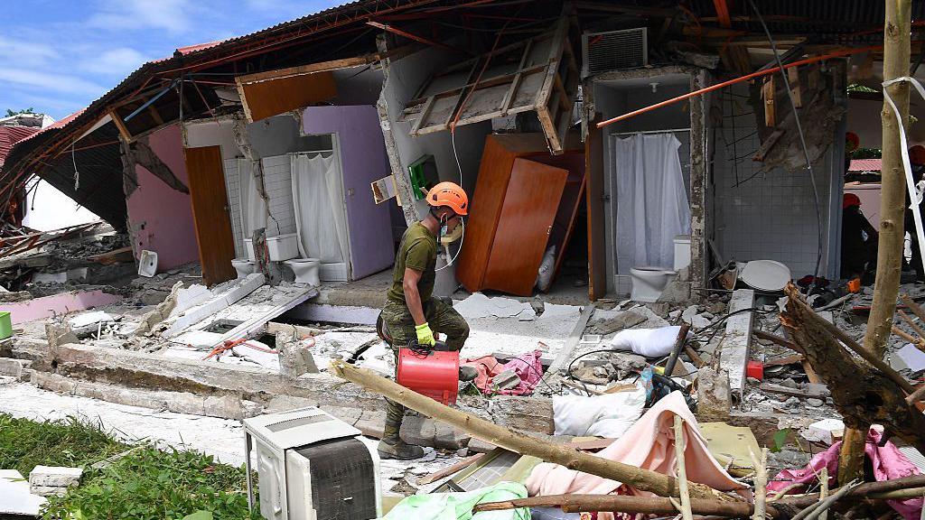 Un rescatista delante de una vivienda derruida en Filipinas. 