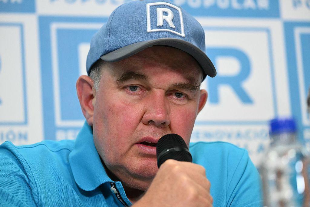 Rafael López Aliaga, con polo y gorra azules, sujeta un micro mientras habla. 