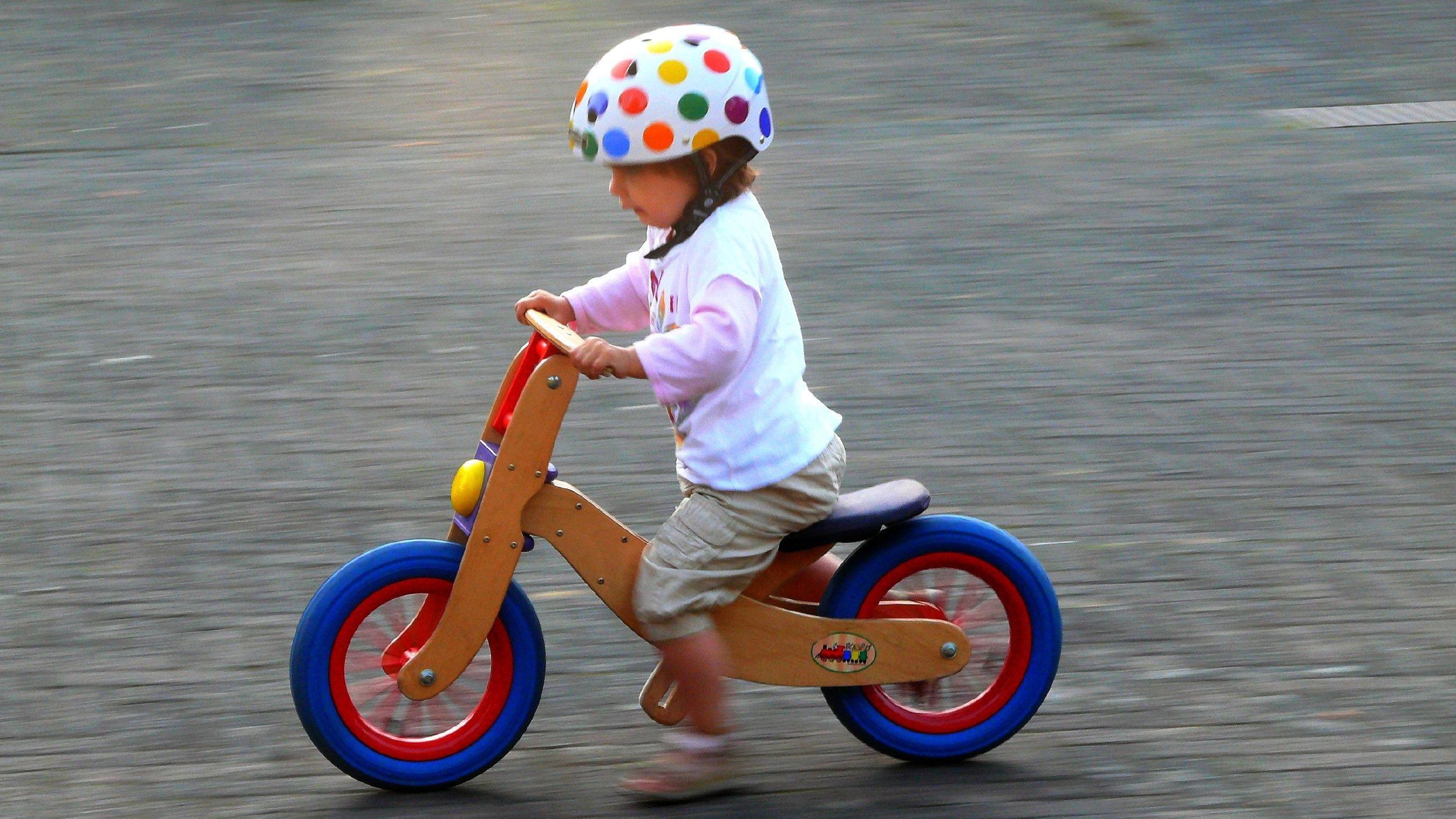 Un niño montando una bicicleta de madera. 