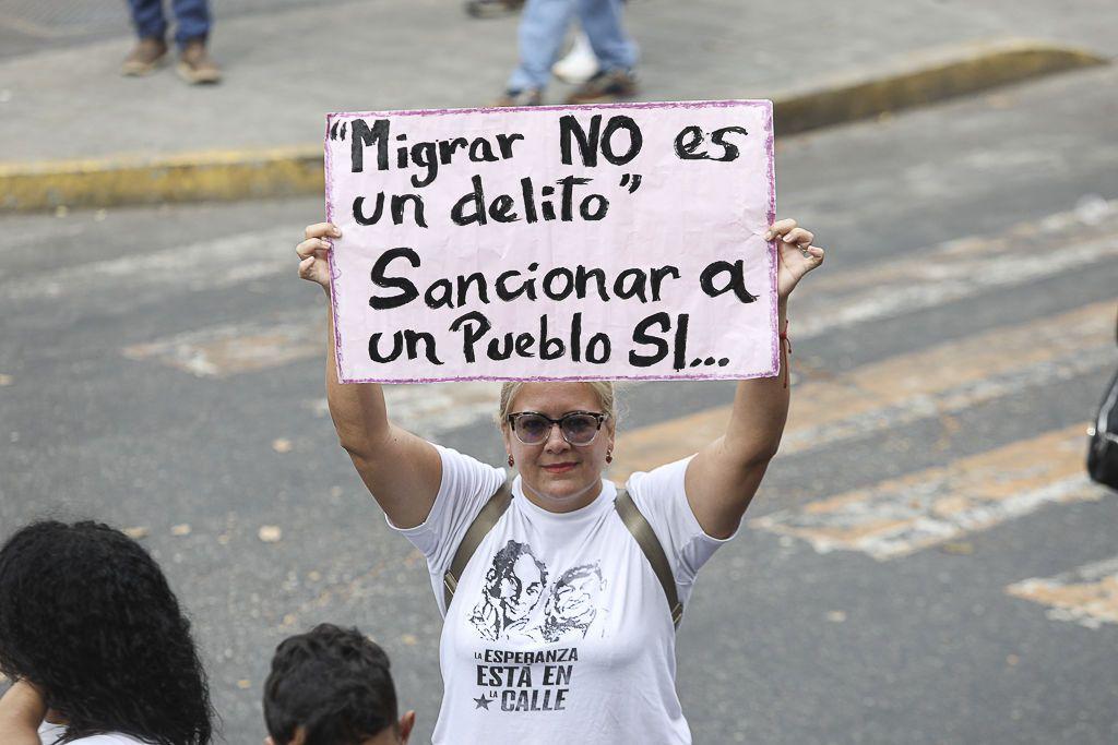 Una mujer sostiene un cartel que dice que migrar no es un delito.