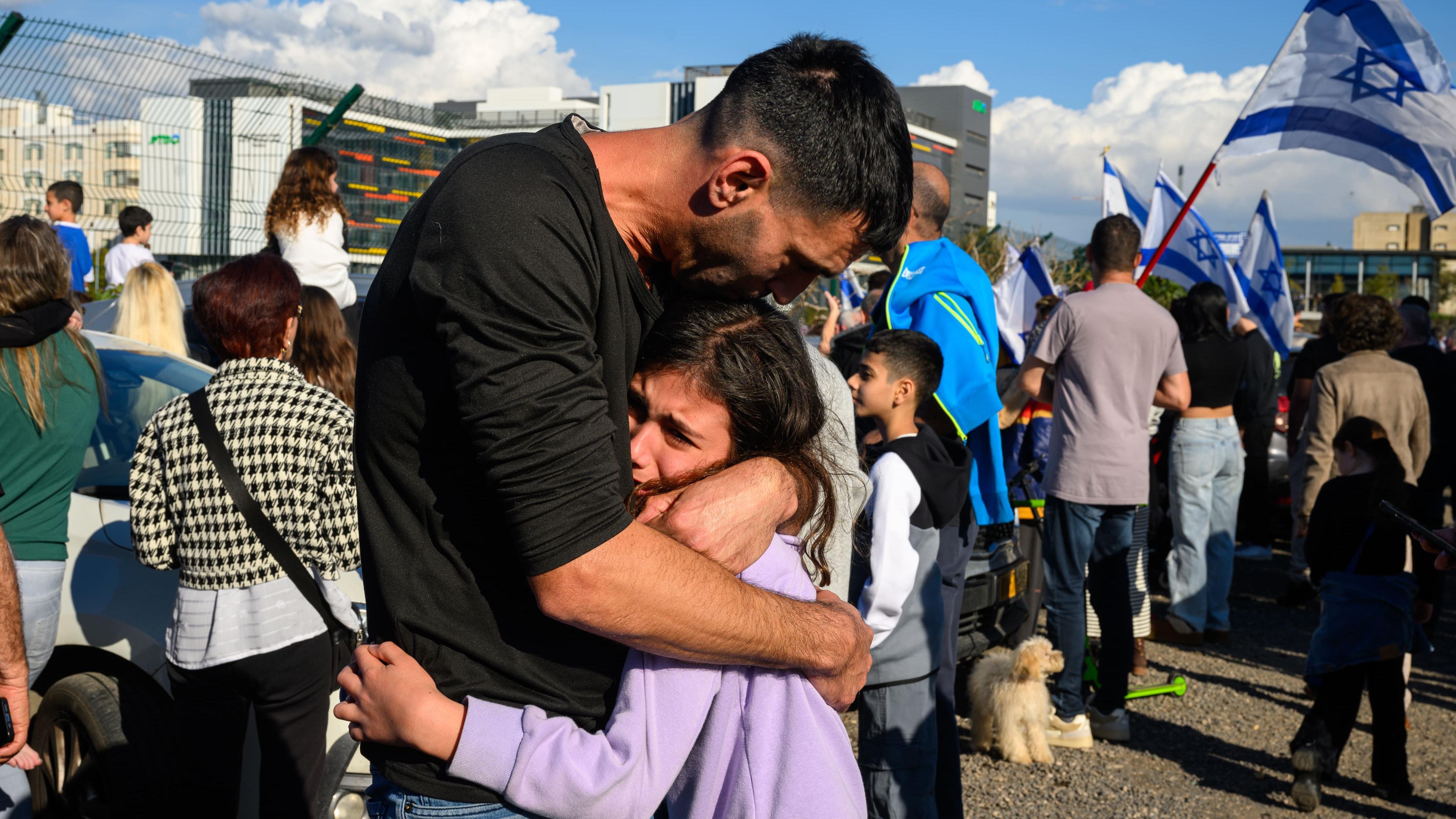 Kako odrastanje u ratu zaista utiče na jednog 11-godišnjaka 13 Otac teši svoju ćerku nakon što je prvi helikopter stigao sa taocima u bolnicu Belinson u Izraelu.