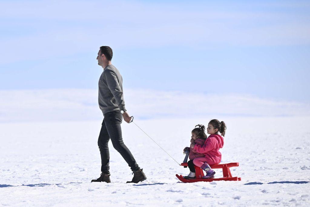 رجل يسحب أطفاله في عربة على الثلج