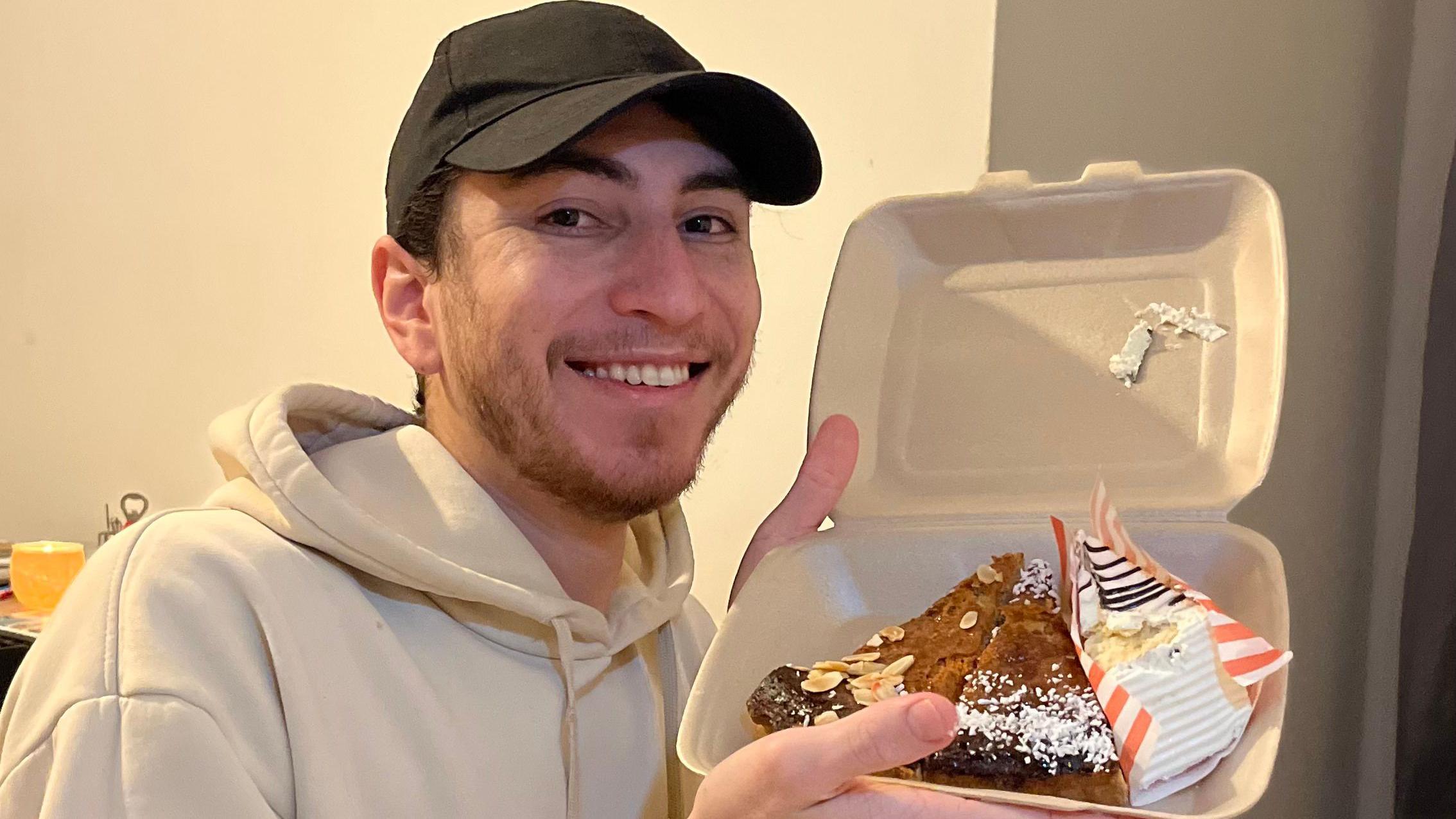 Jovem de bon&eacute; sorrindo ao mostrar comida dentro de embalagem