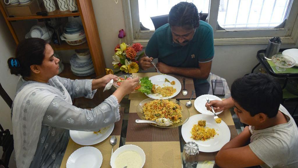Family sitting on a table in their home in Karachi having Sunday lunch 