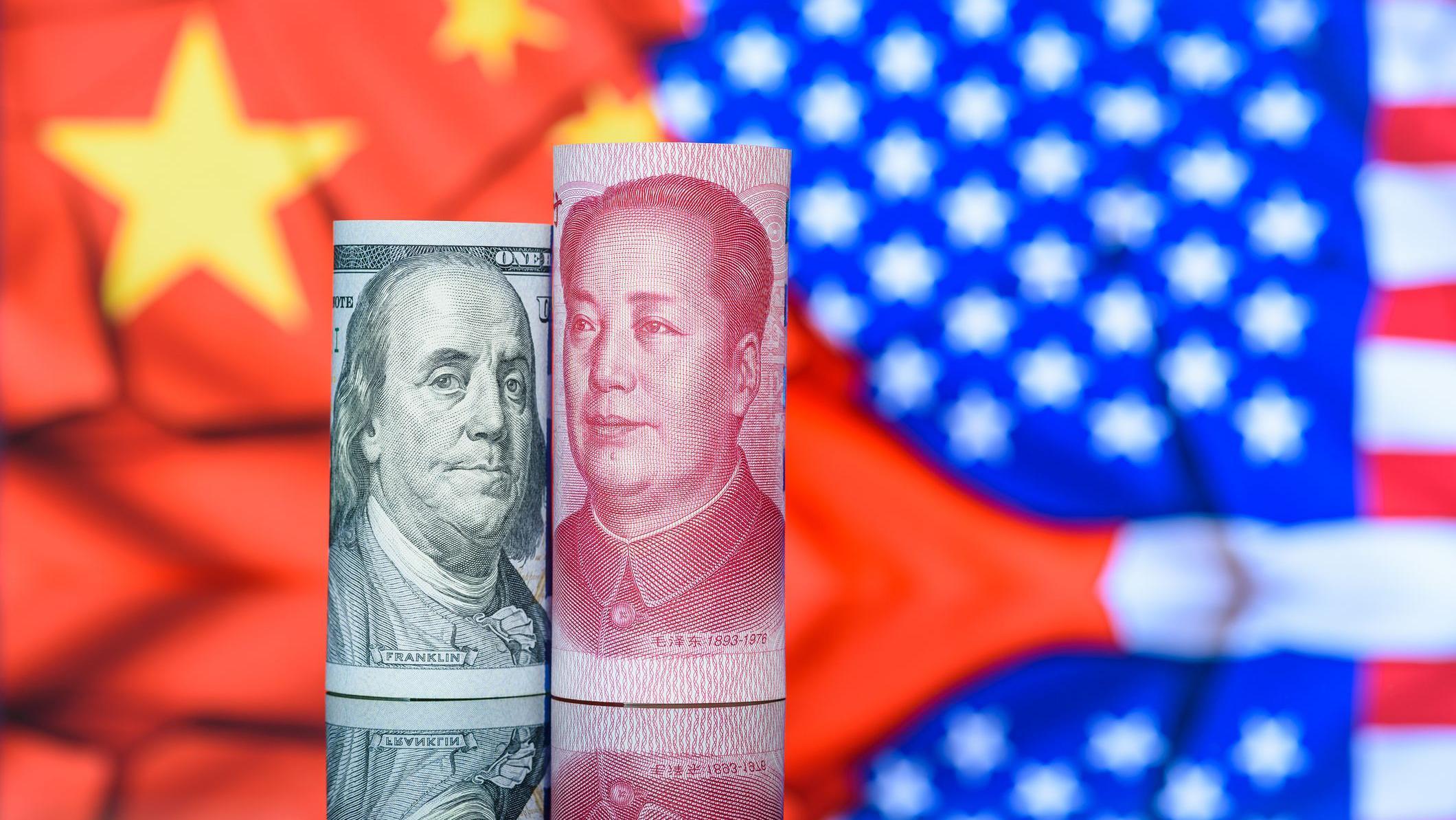 Cédulas dos EUA e da China, em frente a bandeiras dos respectivos países