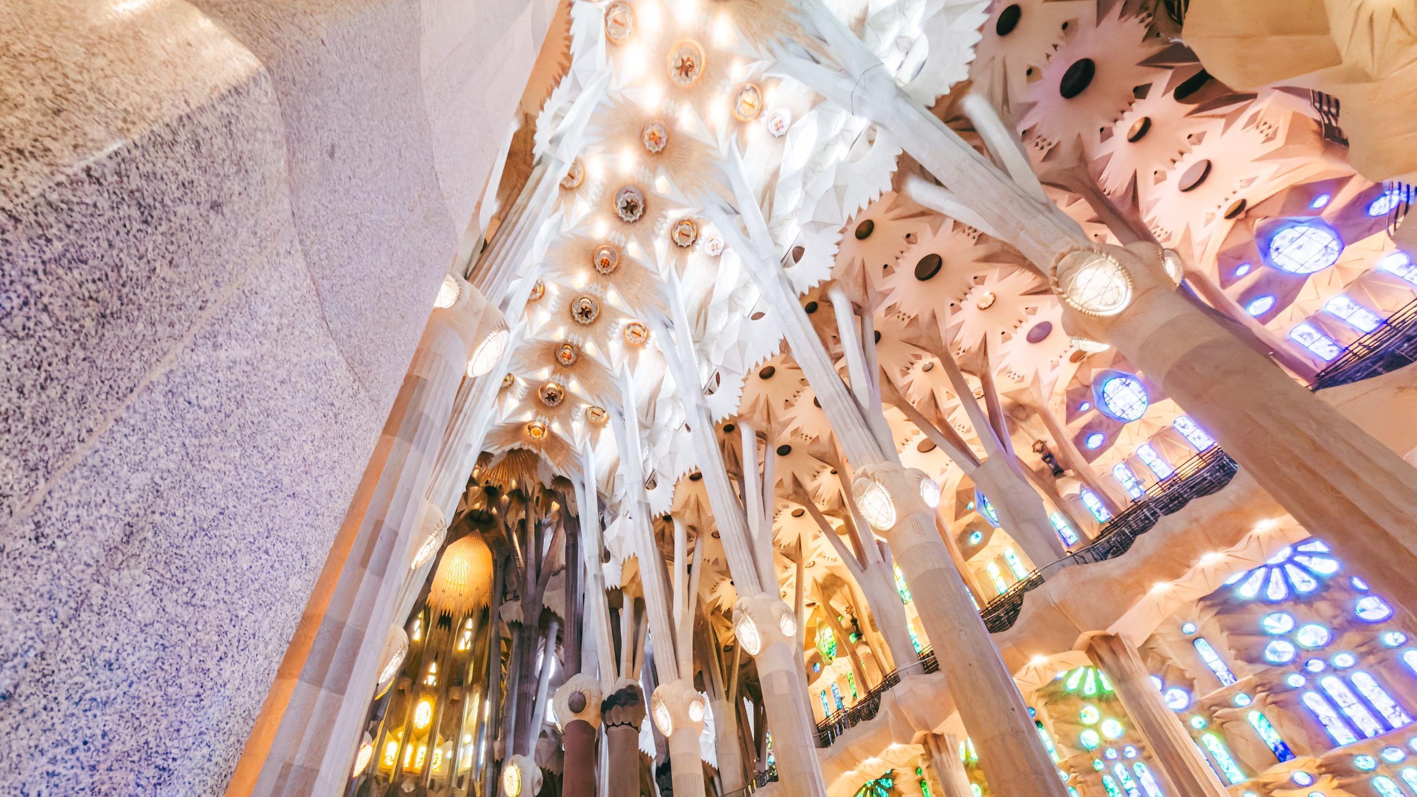Una foto tomada desde abajo de las columnas intrincadamente talladas del interior de la iglesia que se ramifican en la parte superior, sosteniendo su techo.

