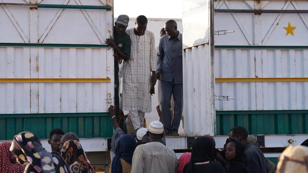 مجموعة من الأشخاص يقفون أمام ما يبدو أنه كرفان ورجل ينزل منها