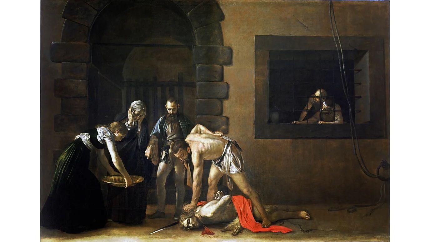 Un cuadro de Caravaggio en el que se ve la decapitación de San Juan Bautista, una mujer está mirando con las manos en la cara, otra mujer prepara una bandeja y un hombre las acompaña. Al fondo se ve a un preso presenciando la escena desde la ventana de su celda.