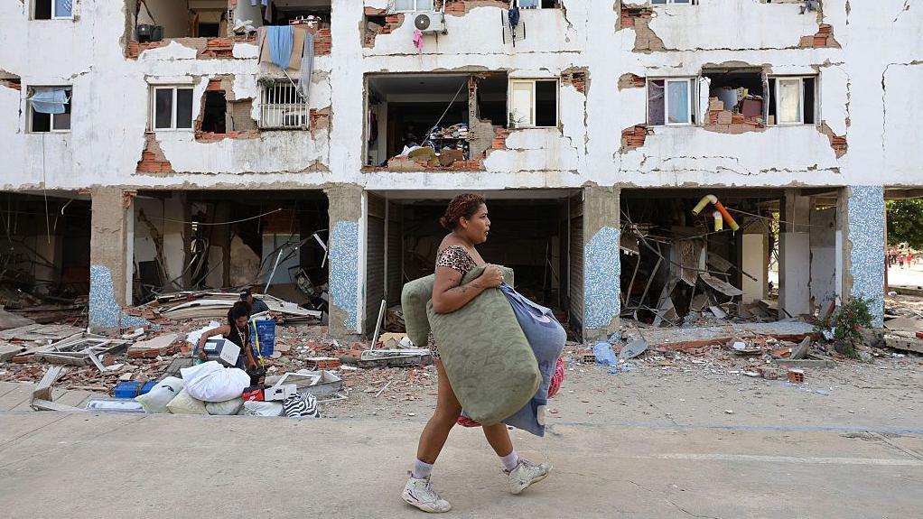Una mujer pasa por delante de un edificio que sufrió extensos daños. 