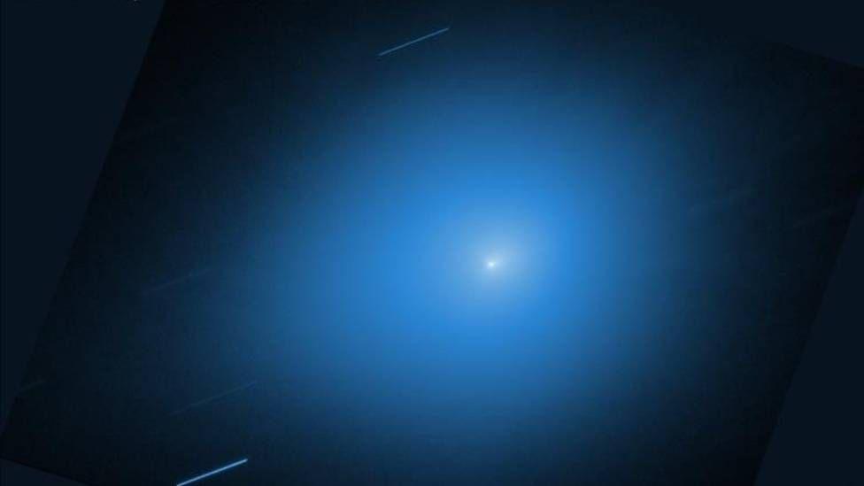 Imagen del cometa 3I/ATLAS en la que se ve en el centro un punto brillante con una estela en un fondo azul claro