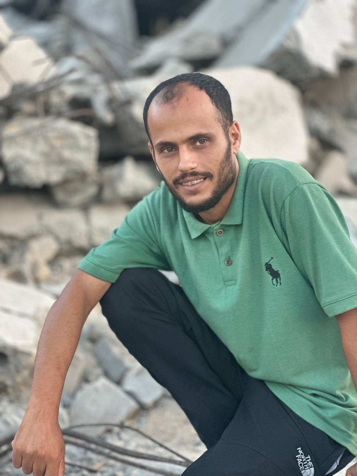 الشاب إياد جالساً على أنقاض منزله المدمر في قطاع غزة