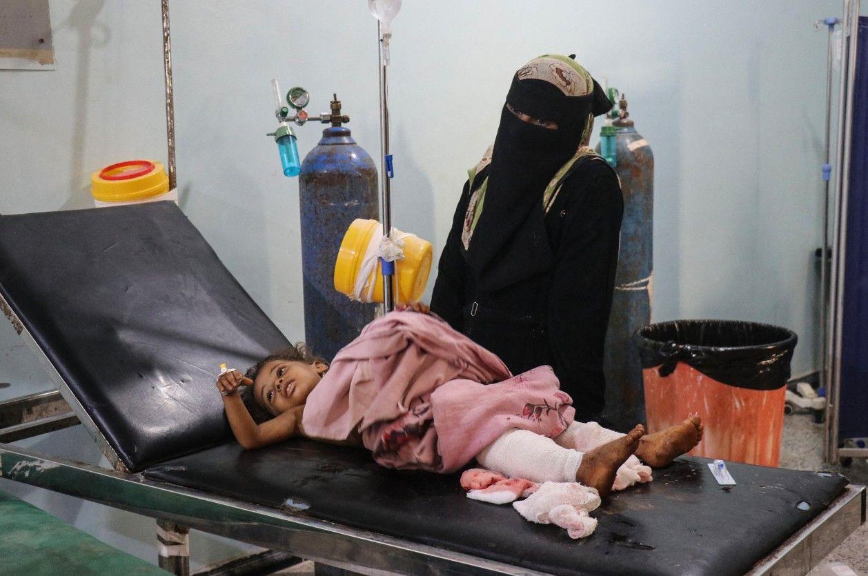 امرأة تقف إلى جانب طفل مصاب يتلقى العلاج في مستشفى، عقب ضربة بطائرة مسيّرة نُسبت إلى الحوثيين في منطقة المشع بحيس، جنوبي الحديدة.