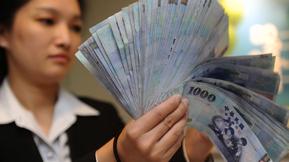 一名女士正在數新台幣鈔票。