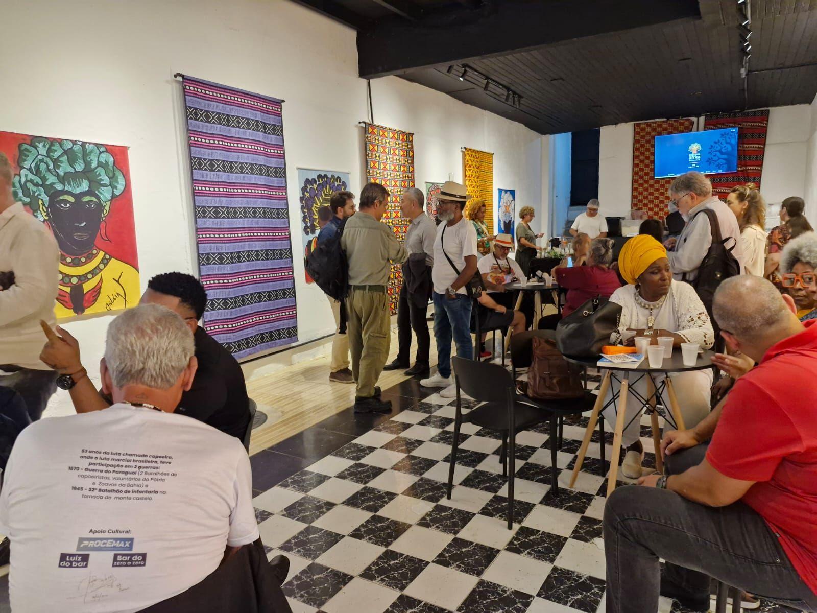 V&aacute;rias pessoas sentadas em um espa&ccedil;o conversando. 