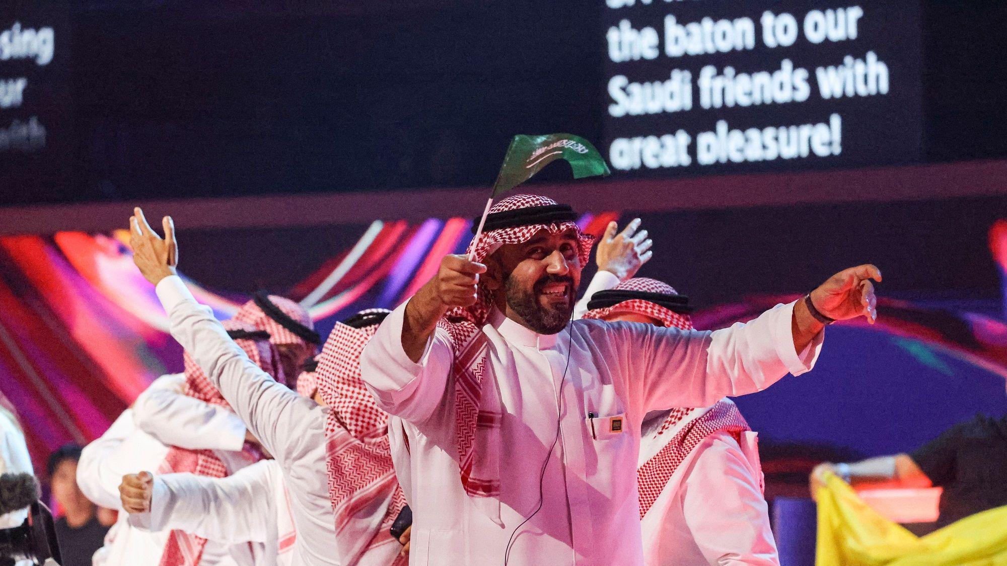 Muškarci u tradicionalnoj saudijskoj odeći slave mašući zastavom svoje zemlje 