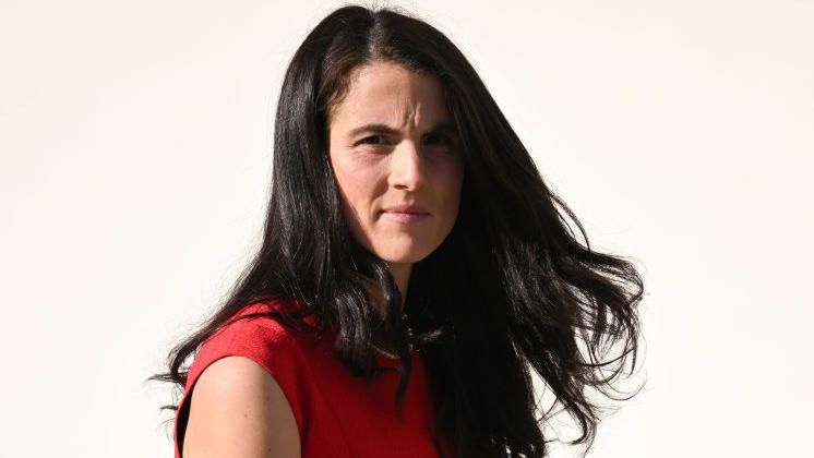 Un primer plano de Tatiana Schlossberg con el cabello largo y un top rojo