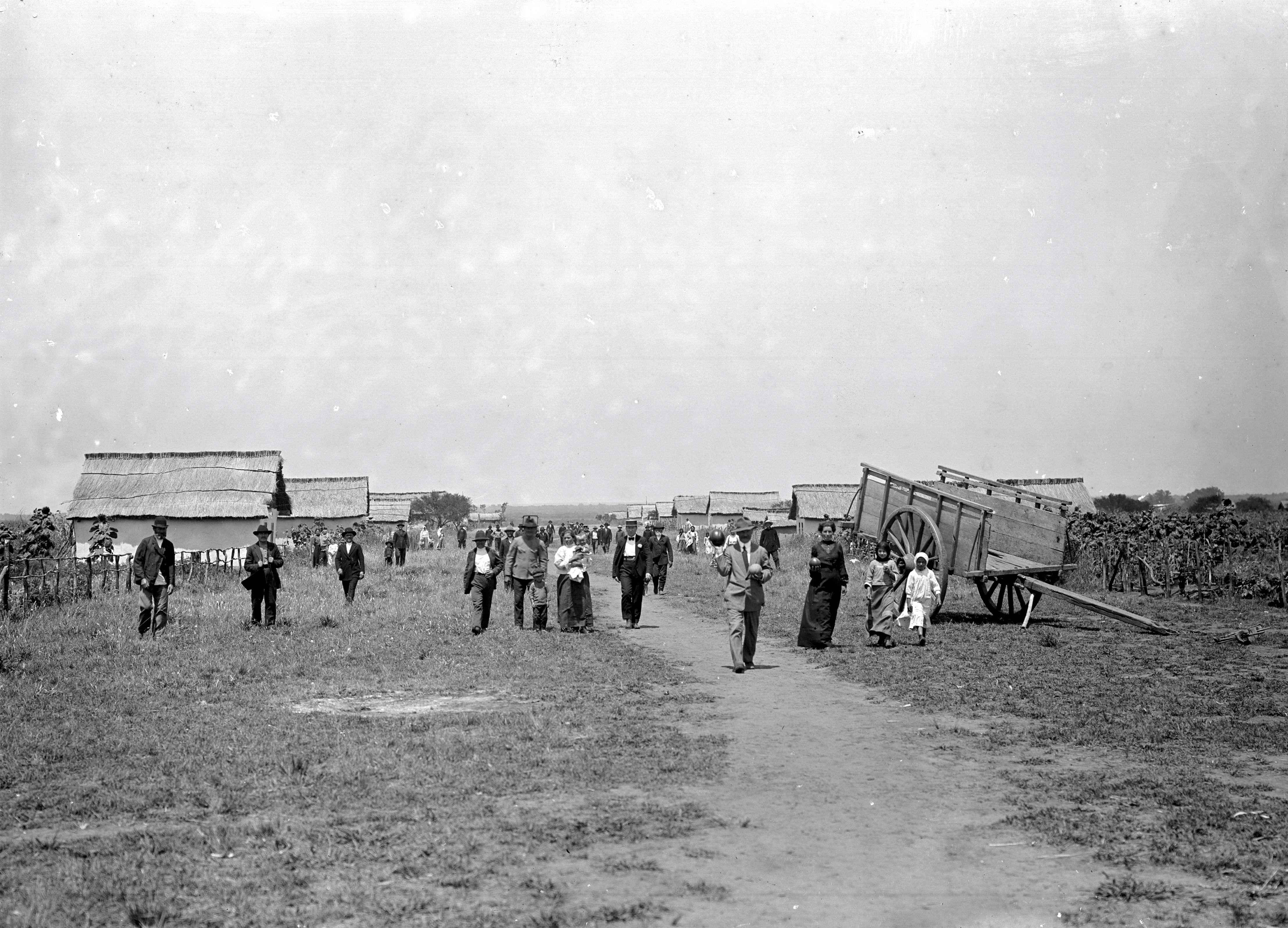 Personas, casas y carretas junto a un camino de tierra en San Javier poco después de la fundación del pueblo por inmigrantes rusos. 