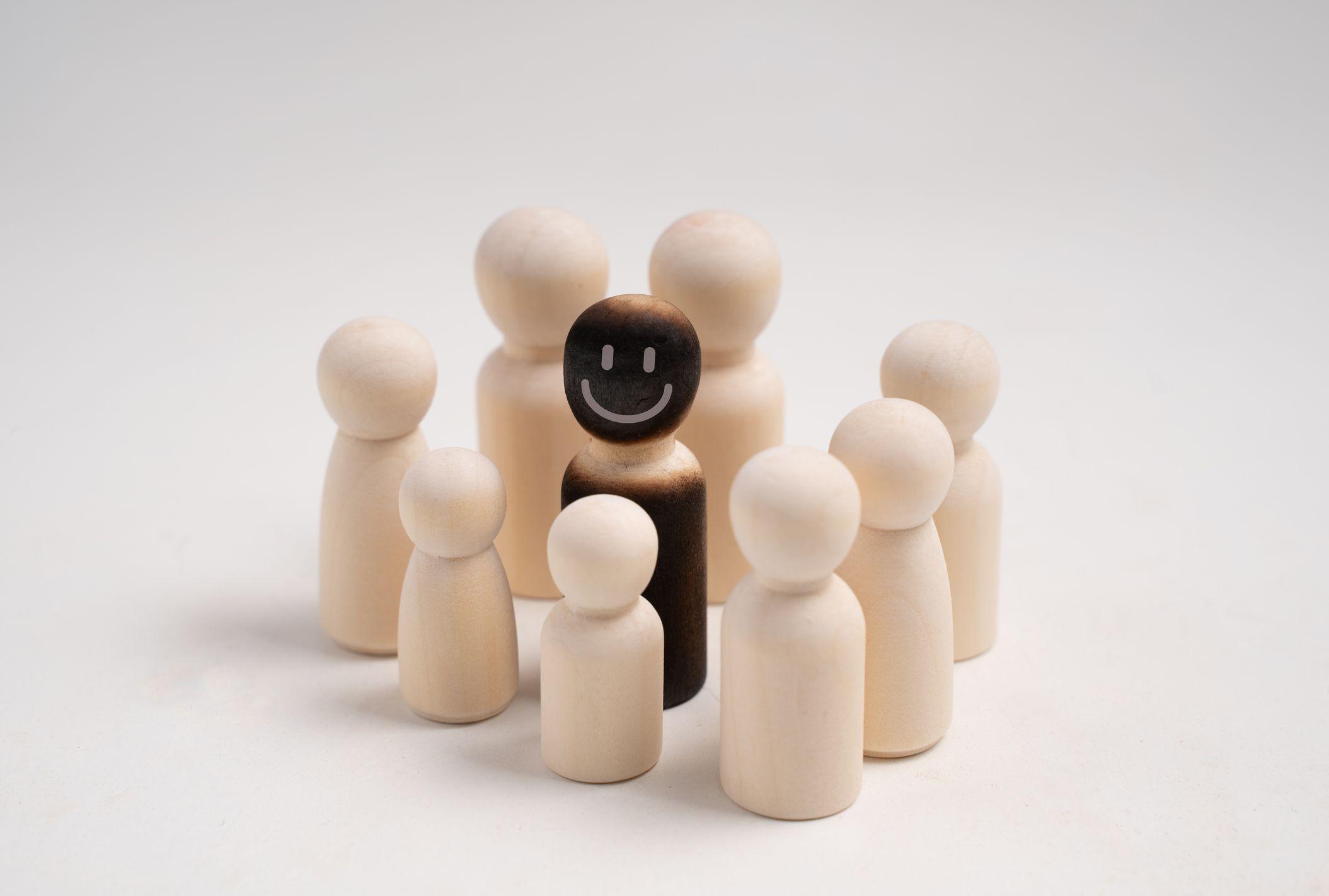 Un grupo de figuras rodean a una de otro color y sonriente. 