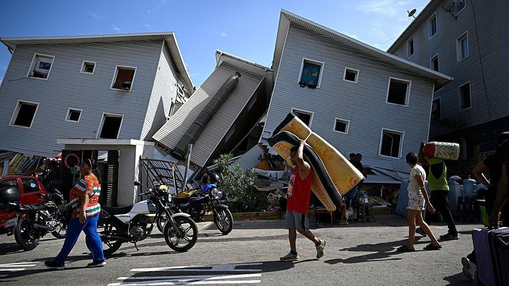 Un hombre transporta un colchón junto a edificios residenciales dañados tras un terremoto en Catia La Mar, estado La Guaira, a unos 30 km al noroeste de Caracas, el 25 de junio de 2026.