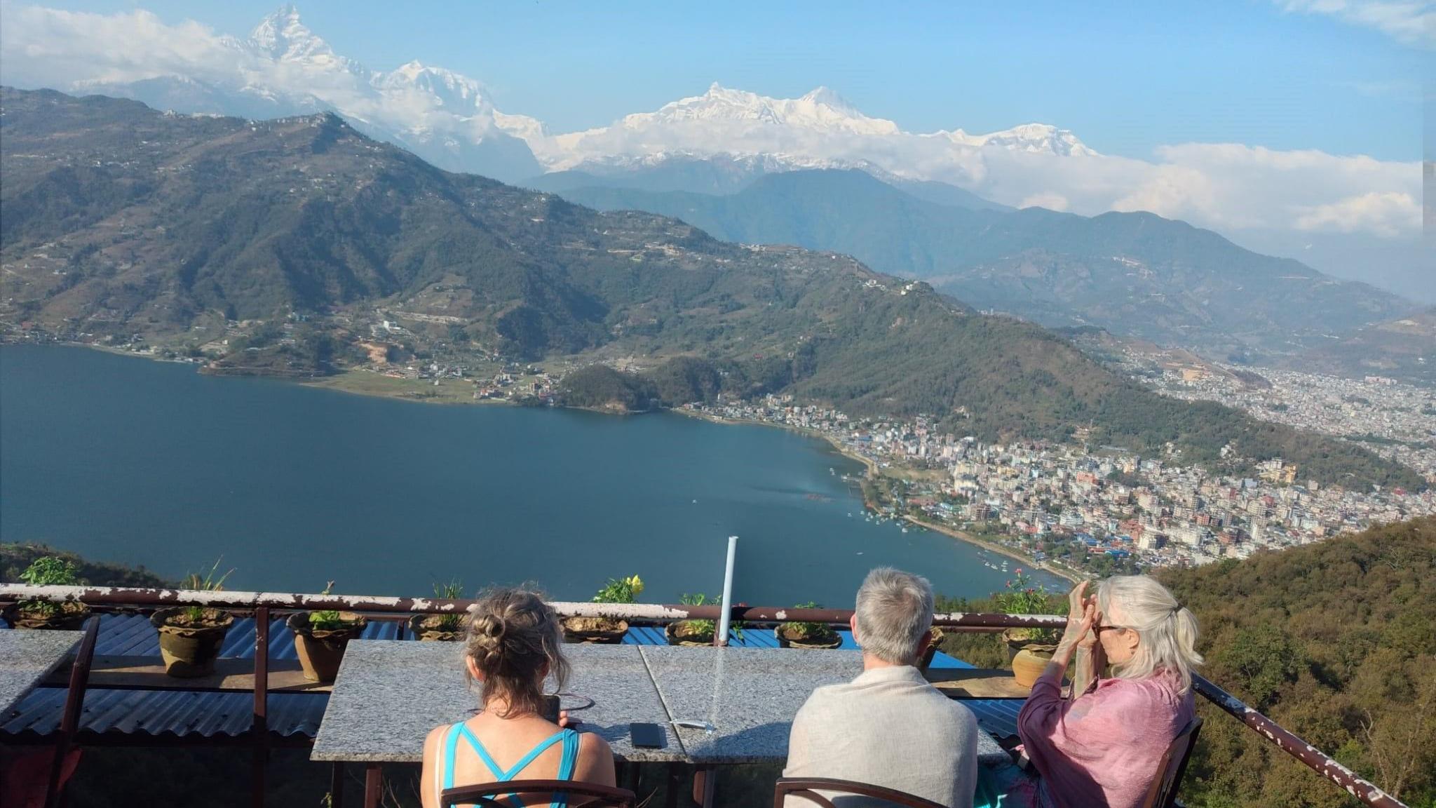 Troje turista sa visine posmatraju Himalaje, okrenuti leđima