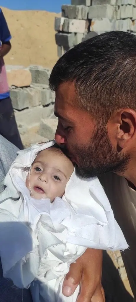 منذر ثلاثيني يميل لونه إلى السمرة شعره أسود وله ذقن سوداء خفيفة. يقبل طفله المكفن بالأبيض.