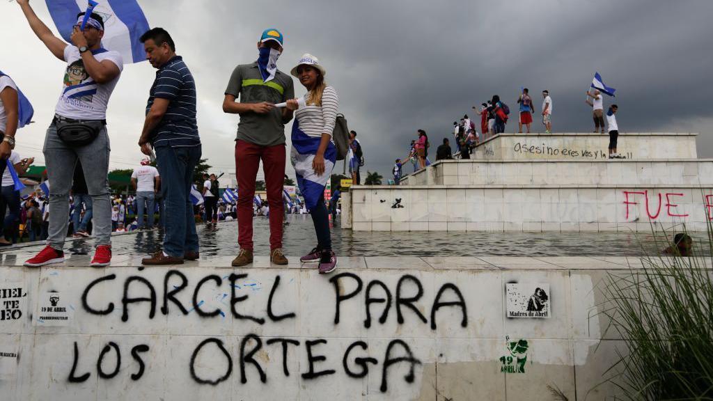 Manifestantes antigubernamentales, de pie sobre un grafiti que decía 