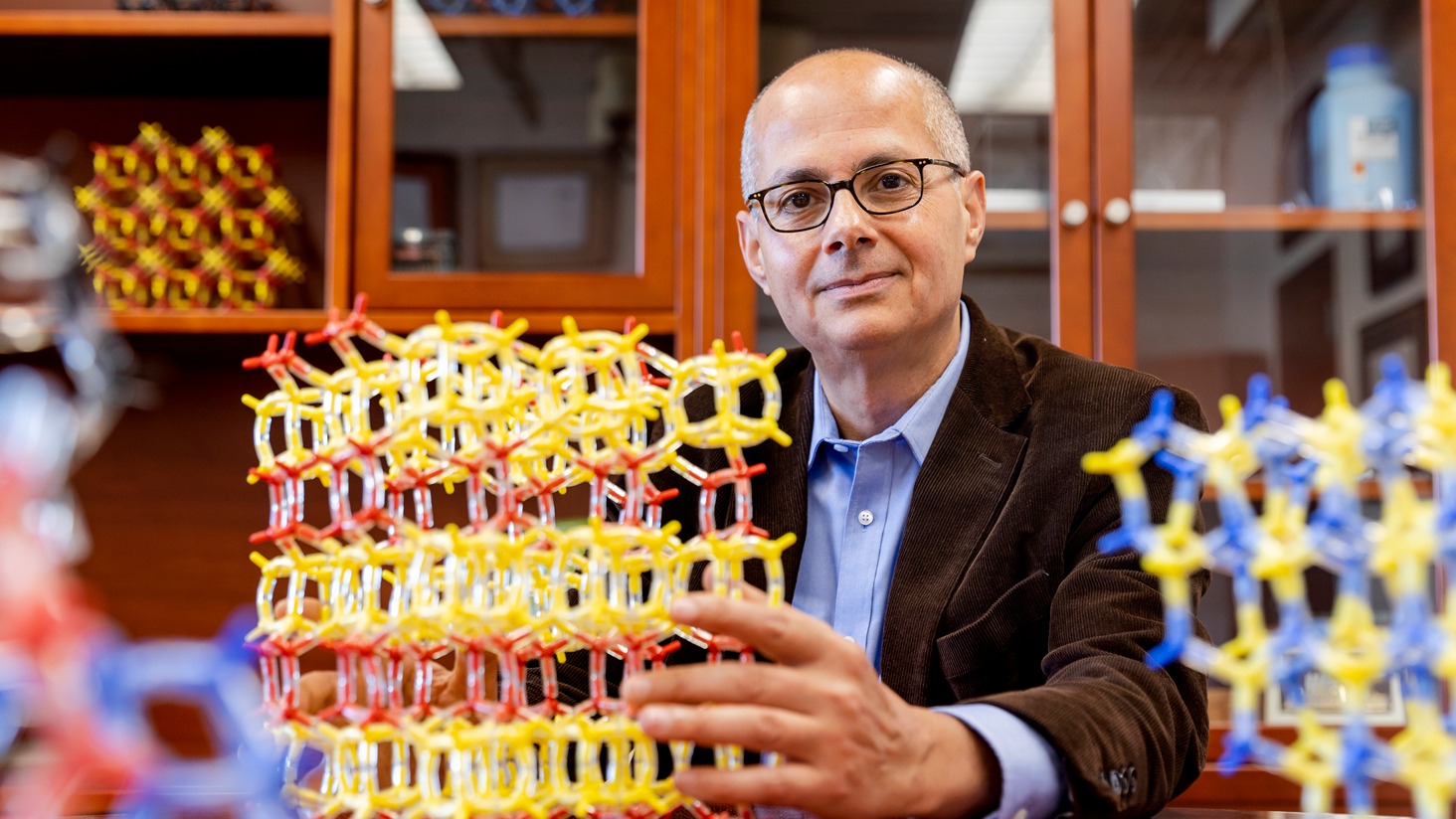 Omar Yaghi sentado con unas estructuras moleculares de colores.