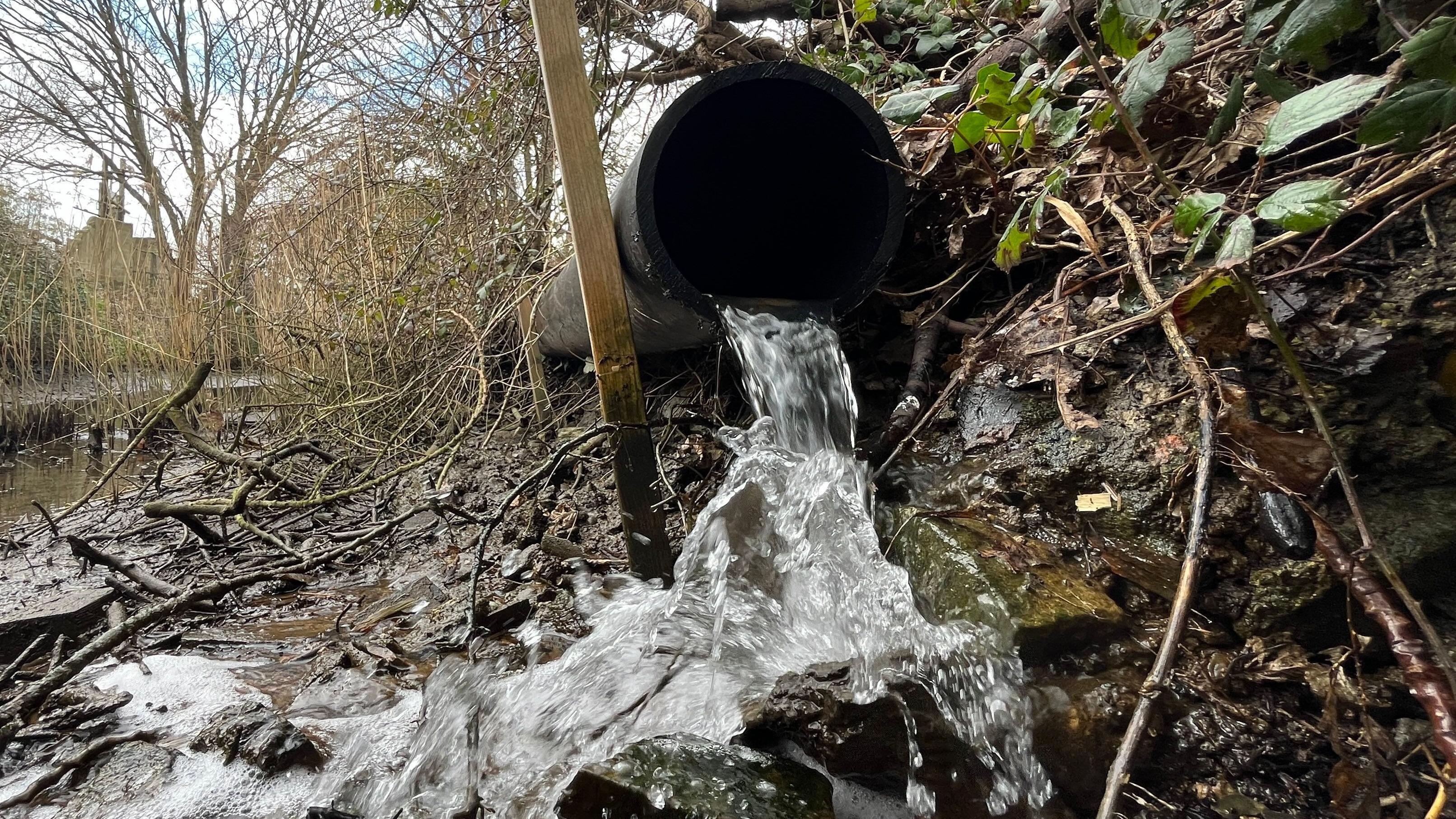 Uma tubulação jorrando água em um riacho