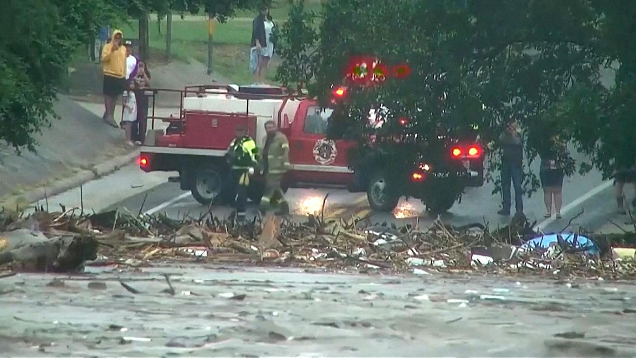 Viatura de socorristas em meio a escombros e pessoas filmando com o celular