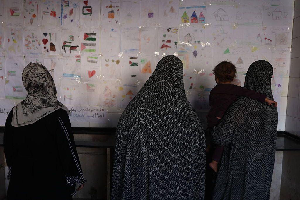 نساء يتأملن مجموعة من الرسومات التي رسمها أطفال في إحدى مدارس النزوح