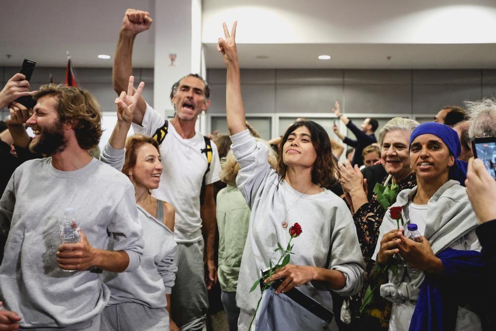 Activistas de la Flotilla Global Sumud saludan mientras reciben ovaciones al llegar a Atenas