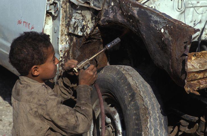 طفل يعمل في تصليح إحدى السيارات في القاهرة.