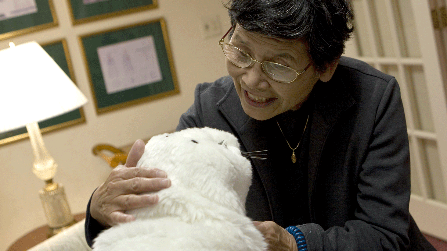 一人正在和外形像小海豹的機器人Paro說話