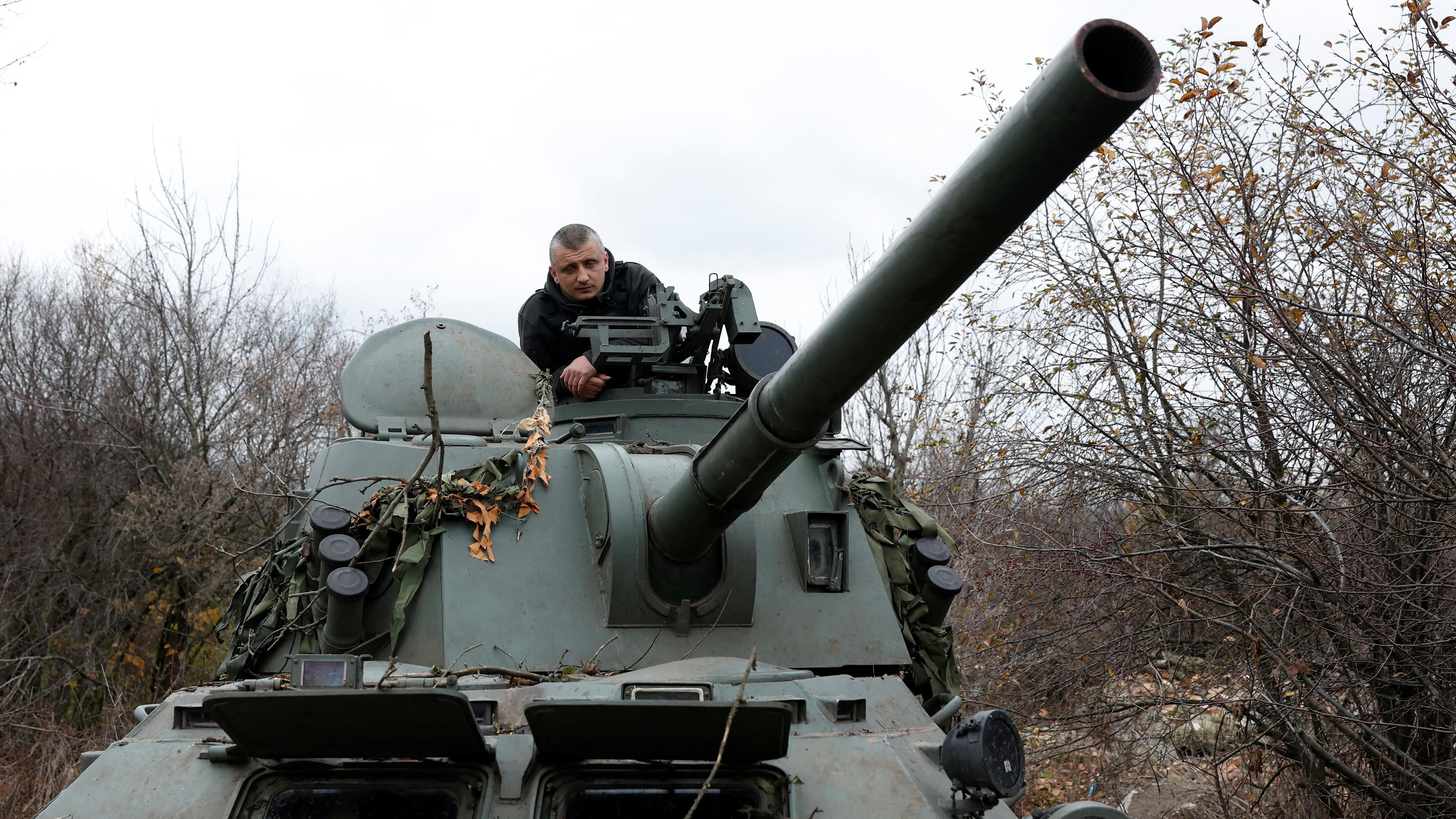 Un soldado observa desde un tanque gris en una zona boscosa. Los árboles están desnudos por el invierno y el cielo está gris. La torreta de un cañón apunta hacia la cámara. Soldados ucranianos se preparan para disparar un proyectil de un mortero autopropulsado 2C23 Nona-SVK en la línea del frente, desde un tanque capturado a soldados rusos en una batalla en Husarivka en marzo de 2022. Esta fotografía fue tomada en la región oriental de Donbás, en Bakhmut, el 4 de noviembre de 2022.
