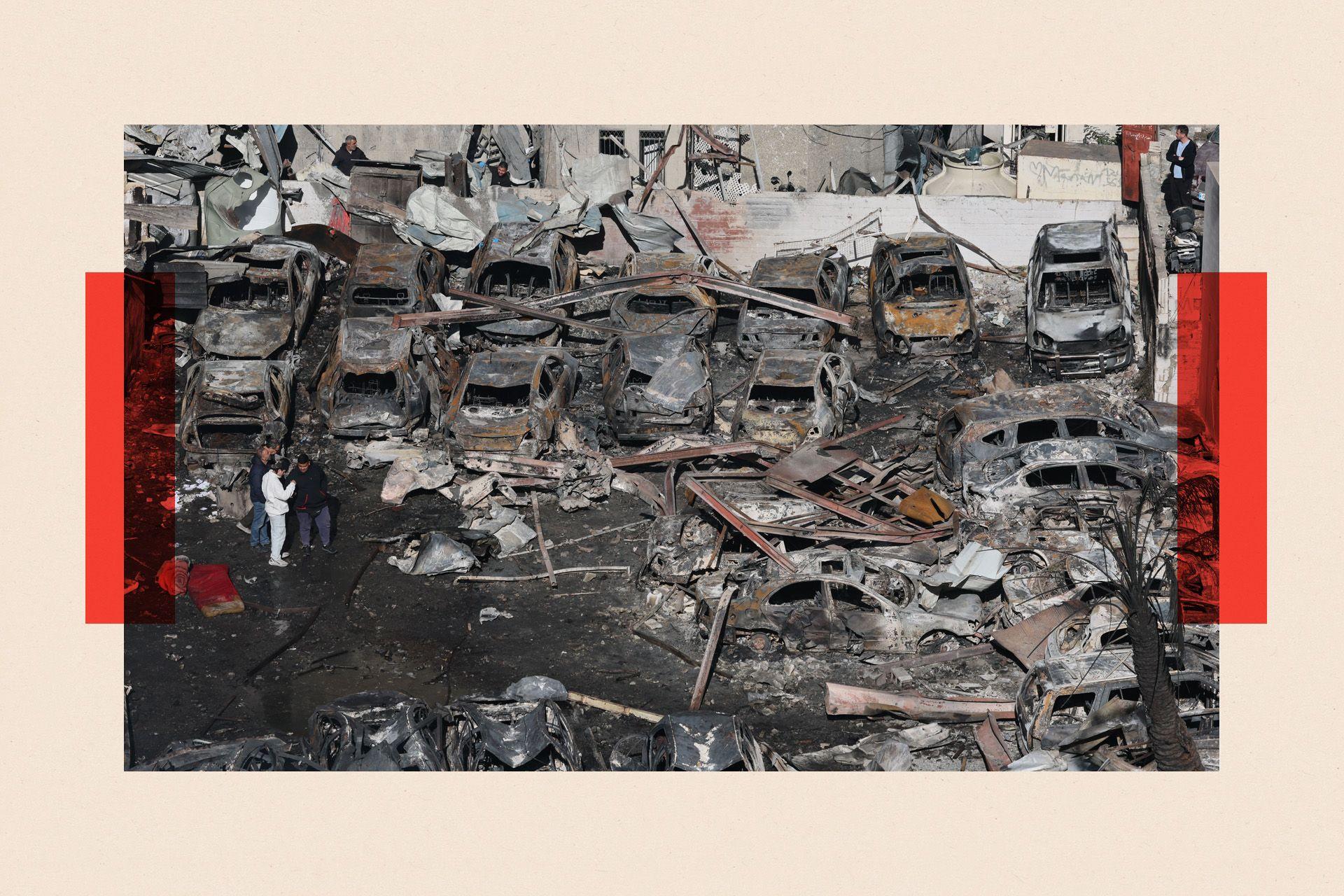 People walk among the debris of cars and a building destroyed in an Israeili airstrike in the Corniche el-Mazraa neighborhood of Beirut