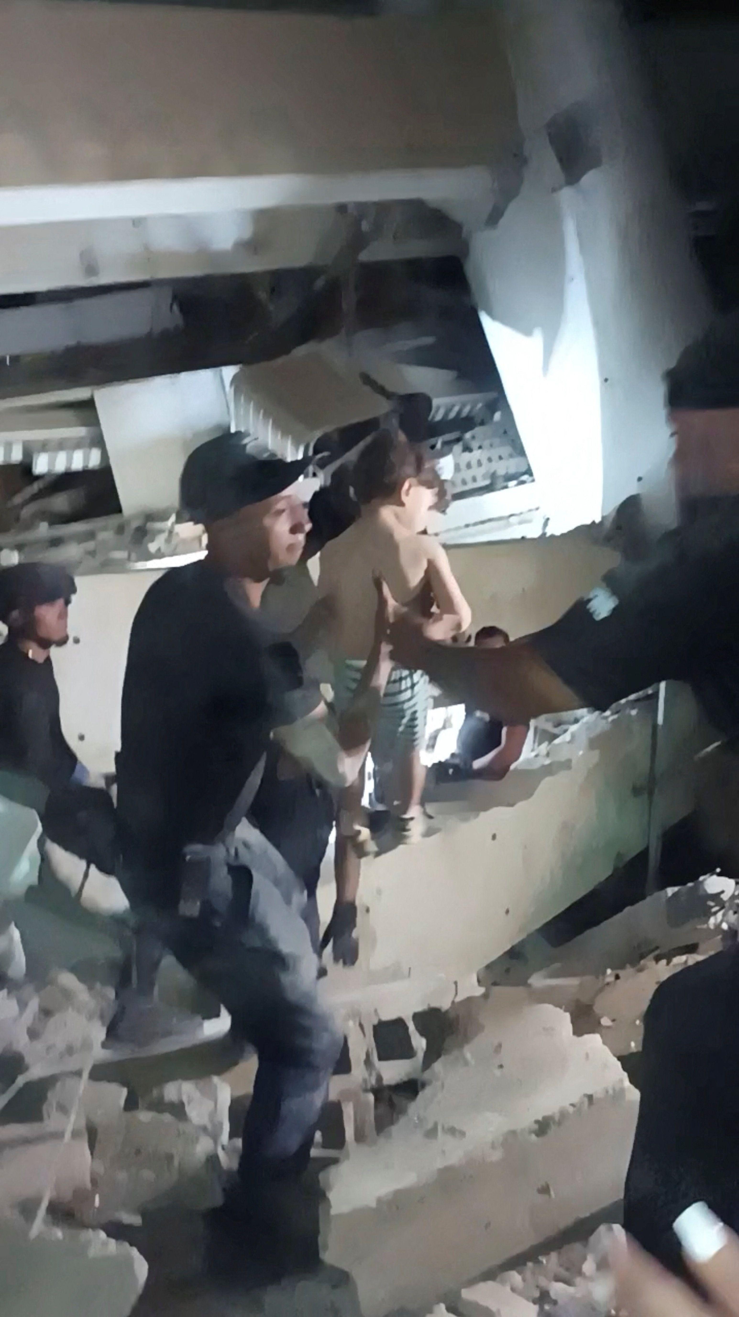 Rescatistas se pasan a un niño pequeño tras ser rescatado de entre los escombros de un edificio, después de que terremotos azotaran el país, en La Guaira.