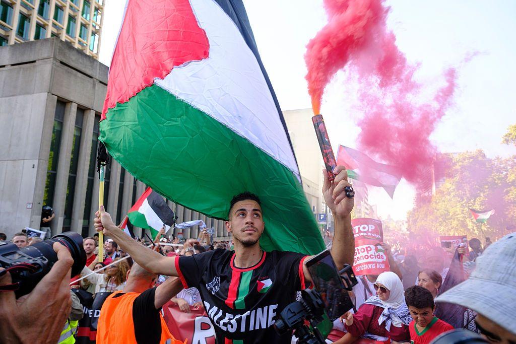 Un hombre sostiene una bomba de humo roja y una bandera palestina mientras manifiesta en las calles de Bruselas, el 7 de septiembre de 2025, en Bruselas, Bélgica.