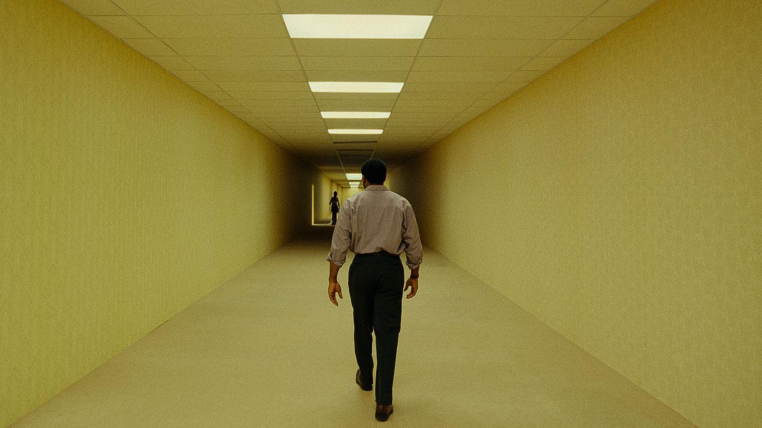 Chiwetel Ejiofor, de espaldas, camina por un largo corredor de paredes y techos de tono amarillo