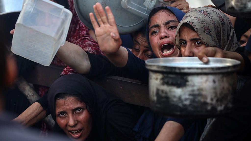Mujeres en Gaza intentan recibir comida en un centro de distribución.