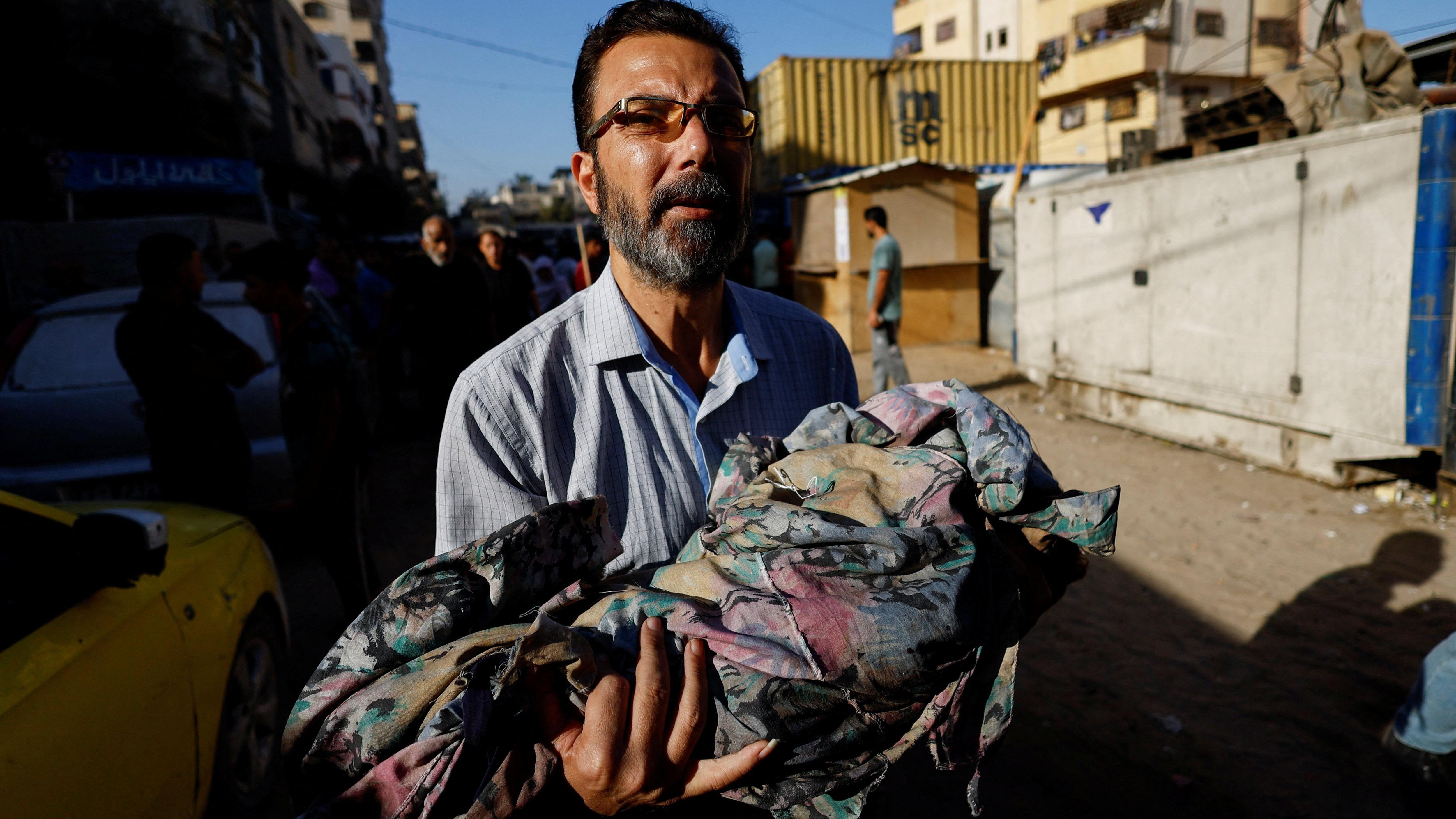 رجل يحمل طفله الذي قتل برصاص الجيش الإسرائيلي في قطاع غزة