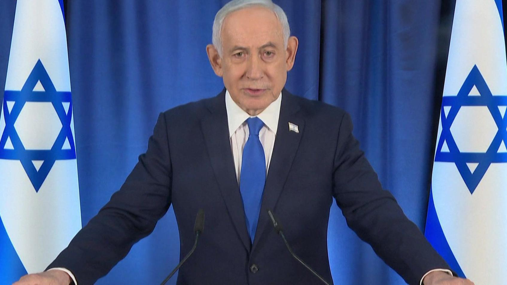 Benjamin Netanyahu, flanqueado por dos banderas de Israel, habla en rueda de prensa el jueves 12 de marzo de 2026. Viste traje oscuro, camisa blanca y corbata azul. Y tiene los brazos extendidos sobre un atril.