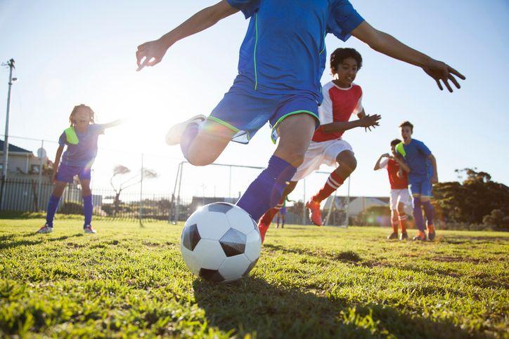 Meninos jogam futebol em gramado 