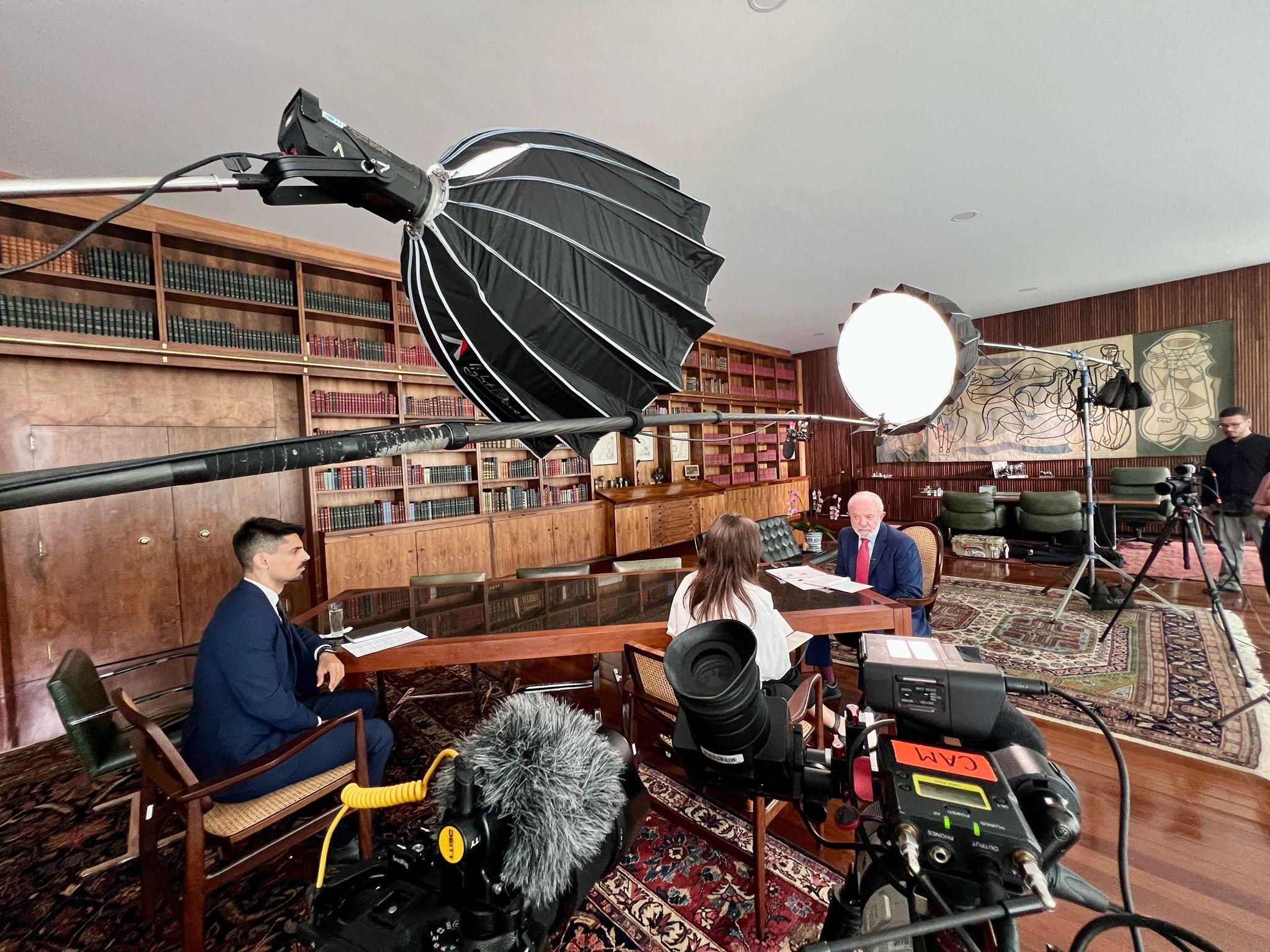 Equipamentos de filmagem em sala; Lula está sentando diante de dois repórteres da BBC