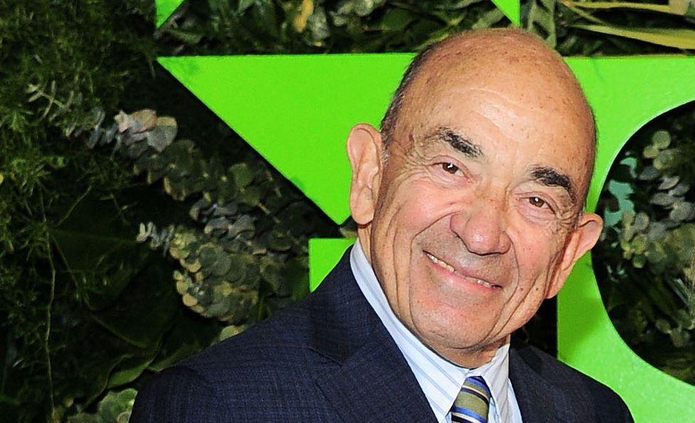 法官艾爾文·海勒斯坦身穿西裝，打條紋領帶，背景是綠色的幾何圖案