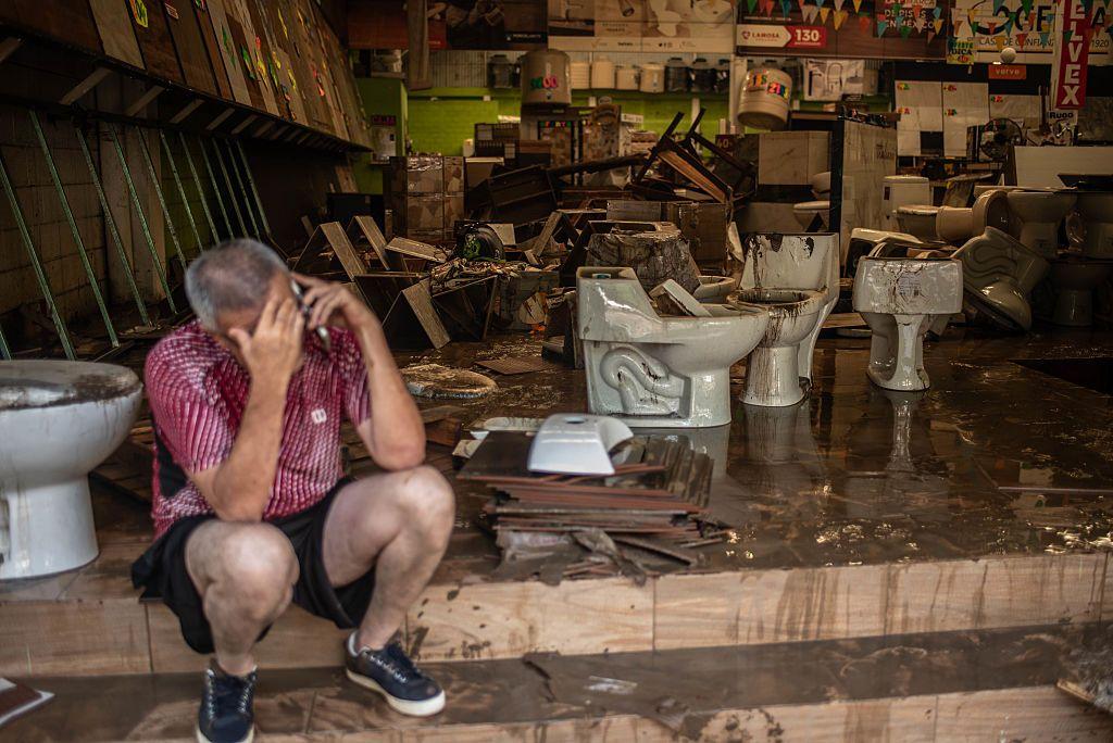 Un hombre habla por teléfono sentado en una tienda de materiales de construcción afectado por las inundaciones