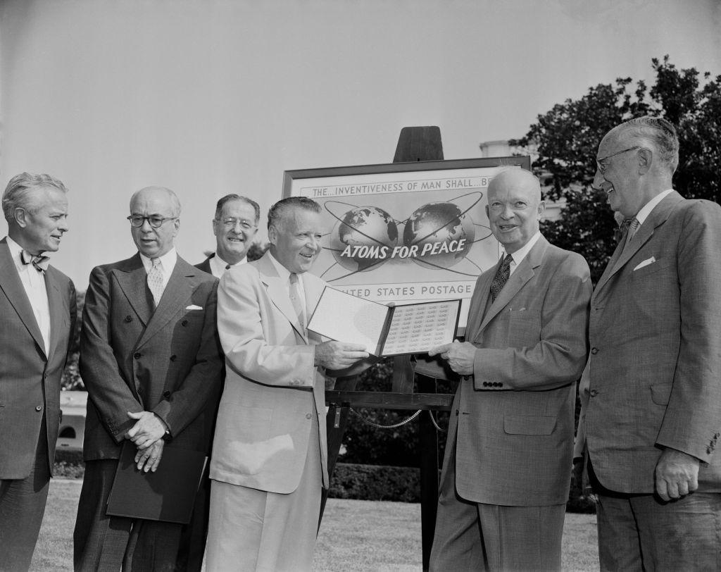 En la ceremonia celebrada hoy en el jardín sur de la Casa Blanca, con motivo de la emisión de un nuevo sello conmemorativo de tres centavos "Átomos para la Paz", el director general de Correos, Arthur Summerfield, entregó una hoja de sellos al presidente Dwight Eisenhower, en compañía de diplomáticos y otros asistentes. De izquierda a derecha: el jefe de Gabinete de la Casa Blanca, Sherman Adams; el presidente de la Comisión de Energía Atómica; Lewis L. Strauss; el senador Clinton Anderson; Summerfield; Eisenhower; y el embajador Wilhelm Munthe de Morgenstierne de Noruega, decano del Cuerpo Diplomático.