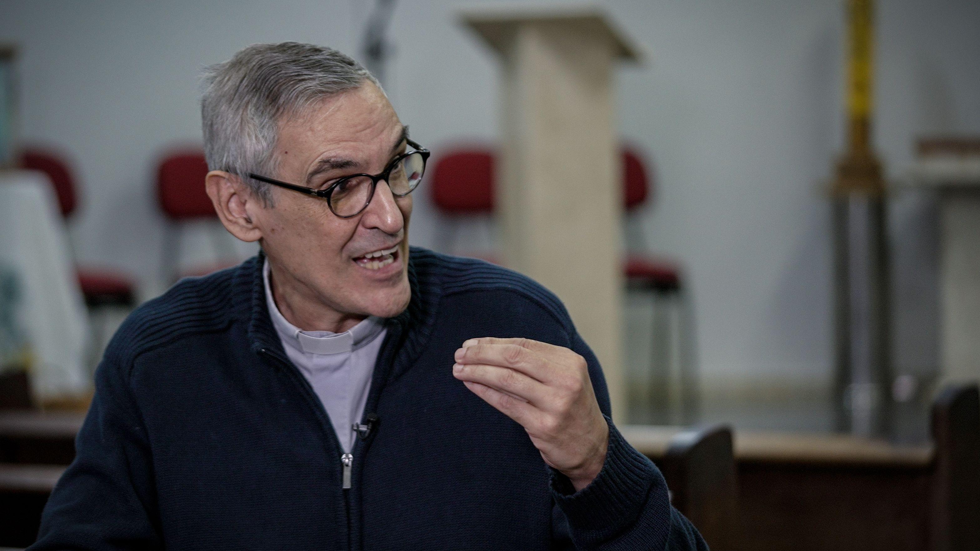 Licio gesticulando enquanto fala em entrevista dentro da igreja