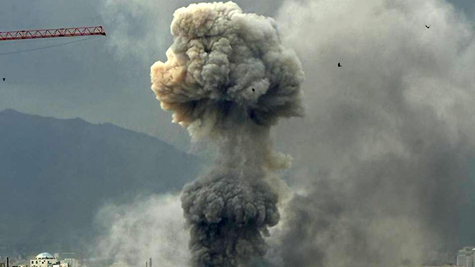 Se observa humo que se eleva desde lo alto de los edificios formando dos columnas, una sobre la otra. A la izquierda se puede ver la pluma de una grúa roja.