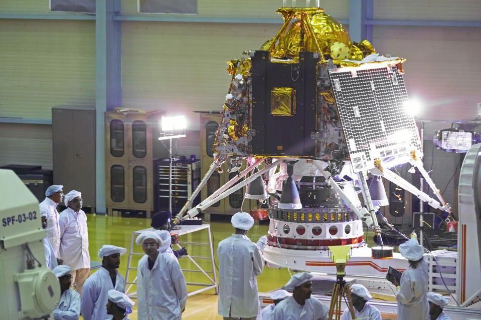 在印度班加羅爾的印度航太計畫總部，幾名科學家站在「月船2號」太空船登陸器旁。